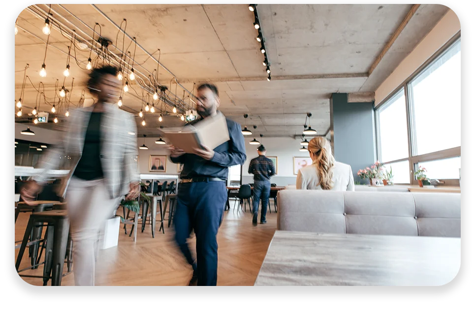 CPQ-Photo-with-two-patterns-three-modules2 An office with cool lighting and business coworkers sitting at a table in a meeting.