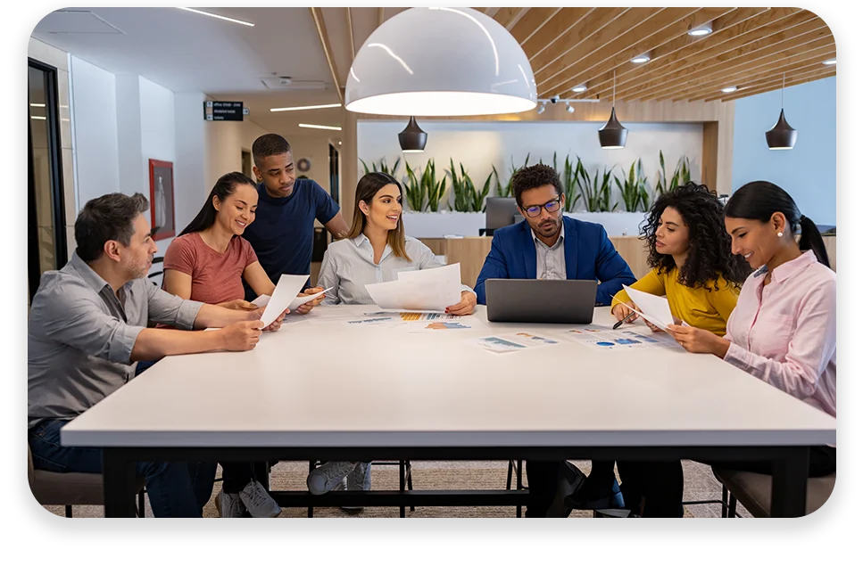 CPQ-Photo-with-two-patterns-three-modules2 An office with cool lighting and business coworkers sitting at a table in a meeting.