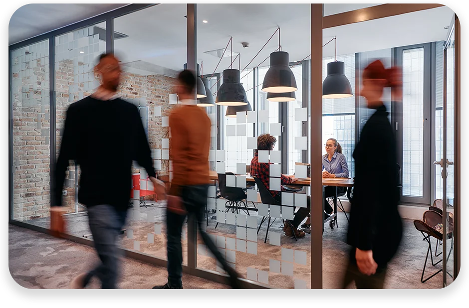 DC13 Ein Konferenzraum in einem Büro, in dem gerade eine Besprechung stattfindet und jemand vorbeigeht.